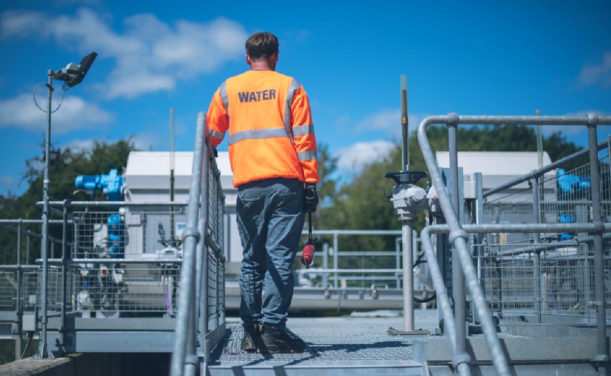 Trabalhador sozinho ao ar livre na estação de tratamento da Wessex Water, no oeste da Inglaterra, Reino Unido.
